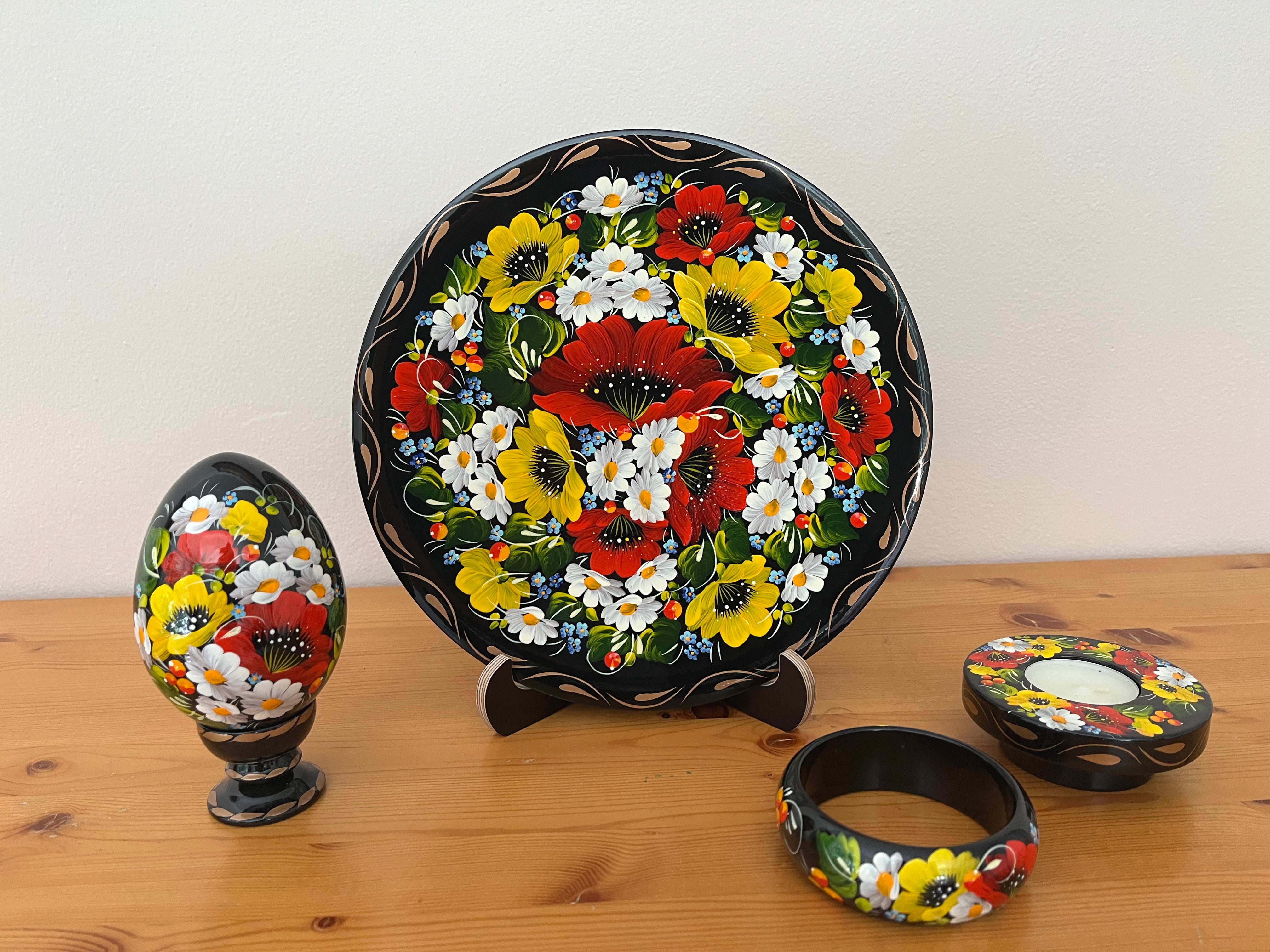 Hand-painted Daisies & Poppies Petrykivka collection featuring a decorative plate, wooden pysanka, candle holder, and bracelet handmade in Ukraine