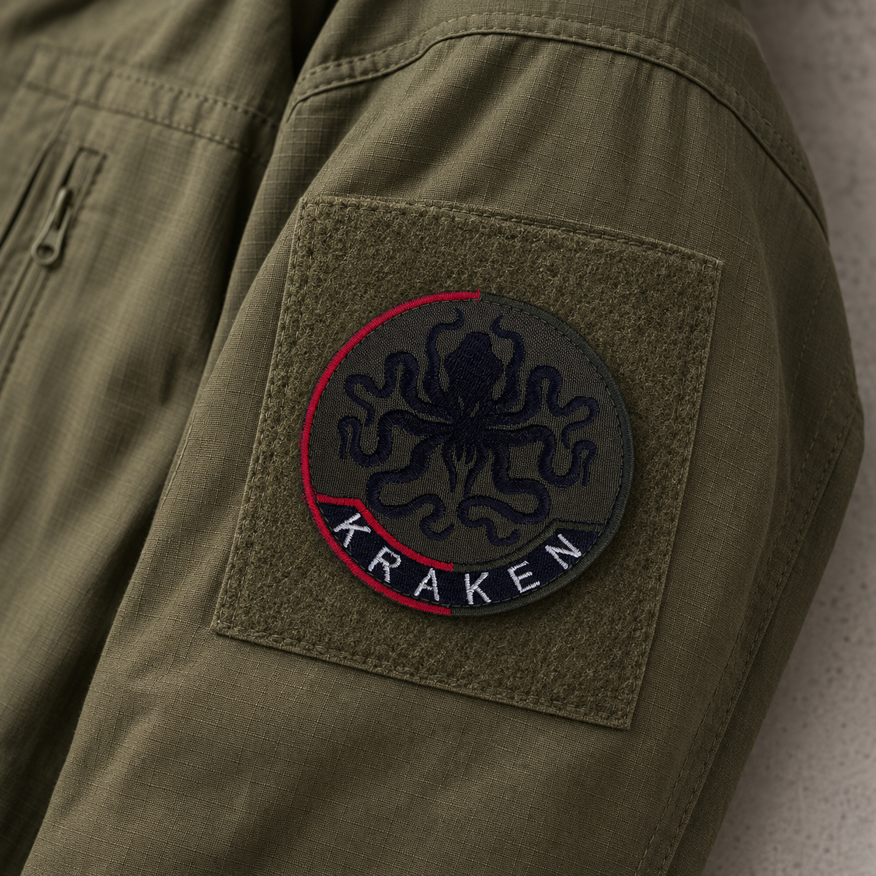 Round Kraken embroidered patch attached to an olive tactical jacket sleeve