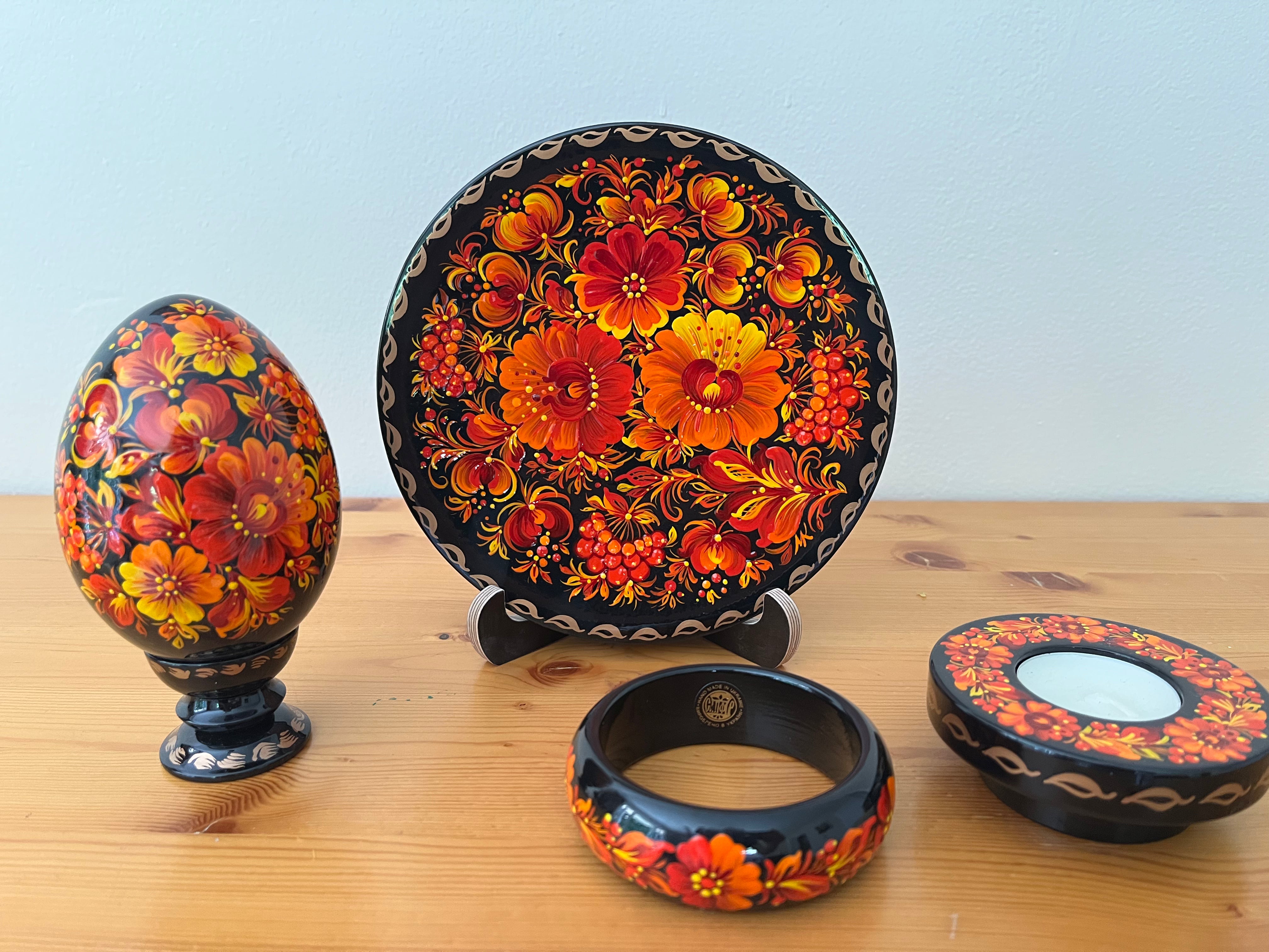 Hand-painted Fire Blossoms Petrykivka collection featuring a decorative plate, wooden pysanka, candle holder, and bracelet handmade in Ukraine